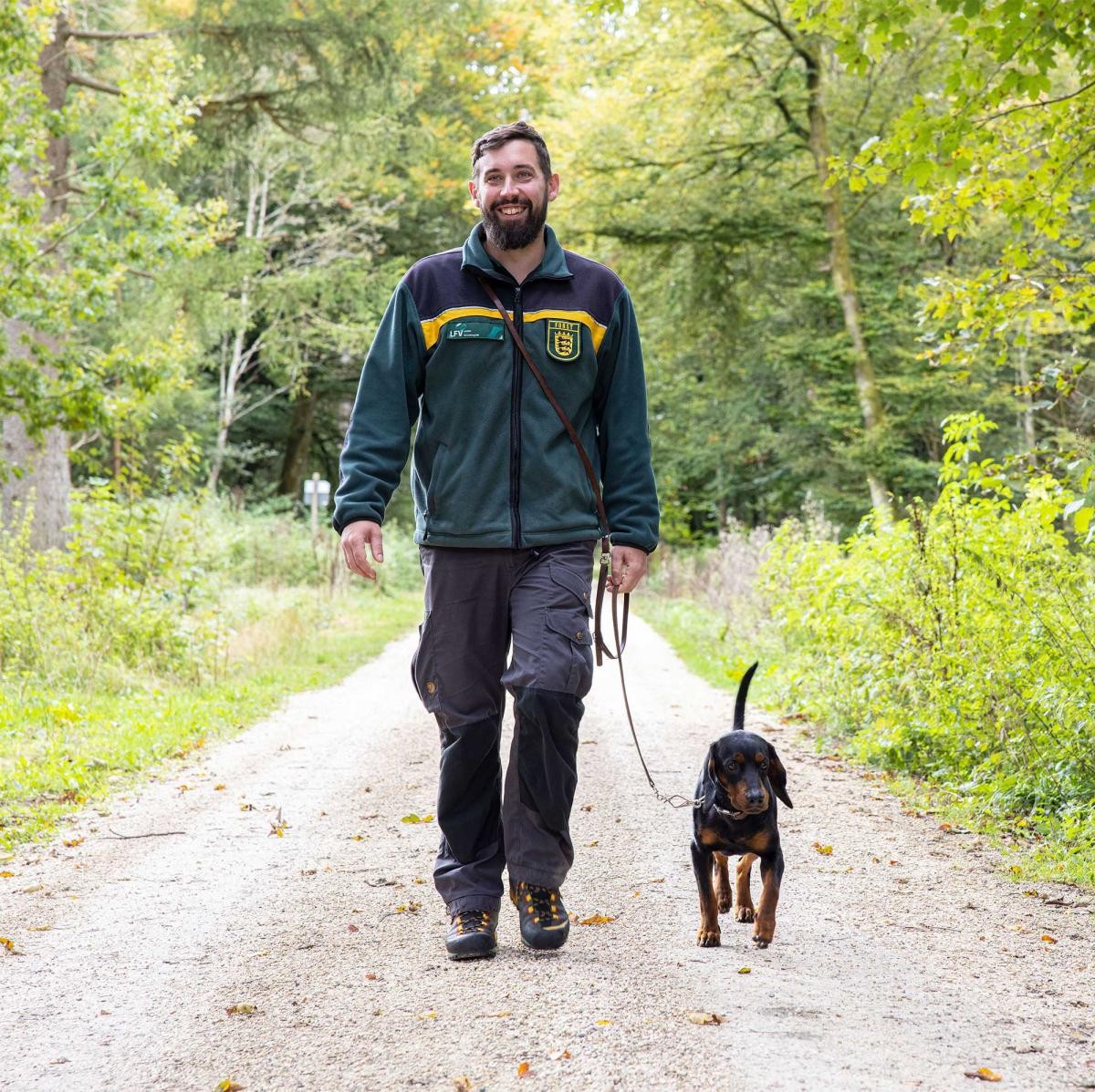 Revierleiter mit Hund auf einem Waldweg